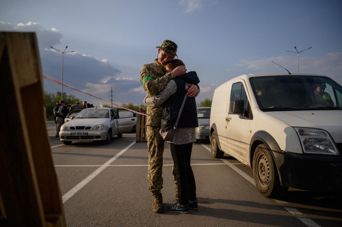 Egy lány néz ki egy buszból, miközben az orosz megszállás alatt álló zaporizzsjai területről származó családok érkeznek egy humanitárius konvojjal a belső menekültek regisztrációs és feldolgozó központjába Zaporizzsjában 2022. április 29-én, az Ukrajna el