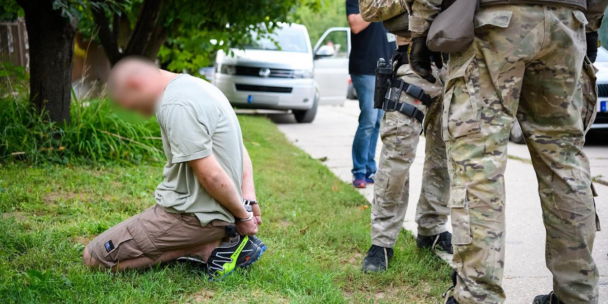 Elfogott gödöllői gyanúsított térdel,mellette TEK-kommandósok állnak