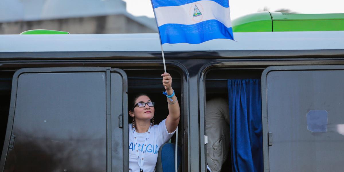 Hazája zászlaját tartja a kezében egy fiatal nicaraguai nő a találkozóra utazva