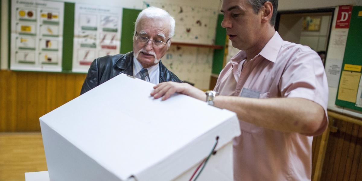 Pirisi László elsőként érkező szavazó (b) és Barta László, a szavazókör elnöke ellenőrzi a szavazóurnát a Mókus utcai Általános 