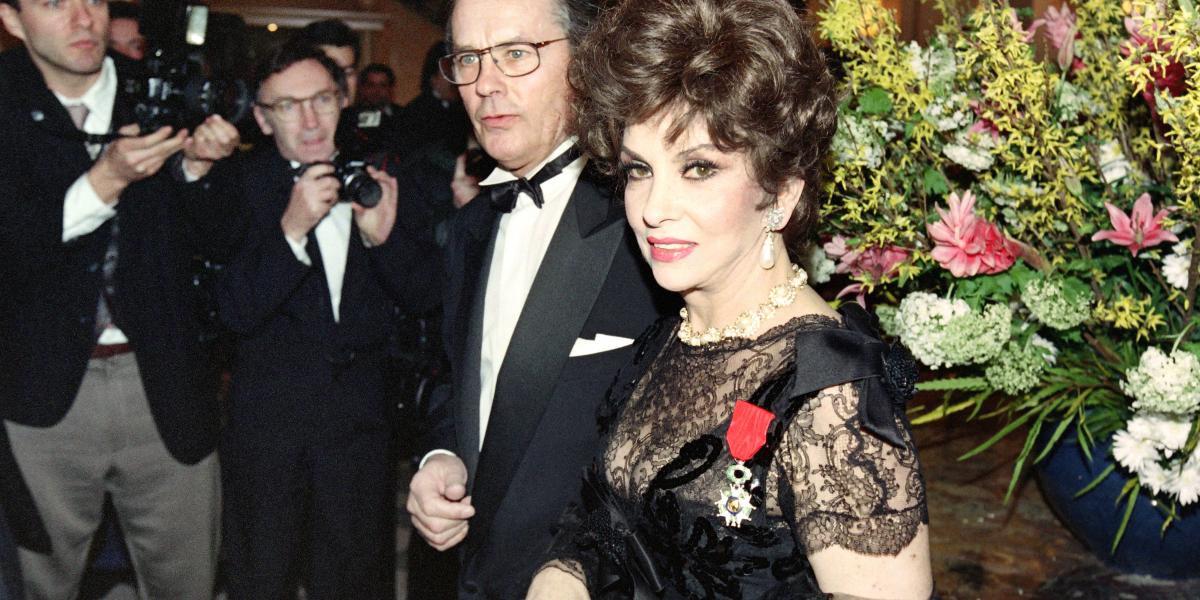 A Becsületrenddel kitüntetett Gina Lollobrigida Alain Delon francia színésszel (középen) érkezik egy párizsi fogadásra 1993. február 17-én.