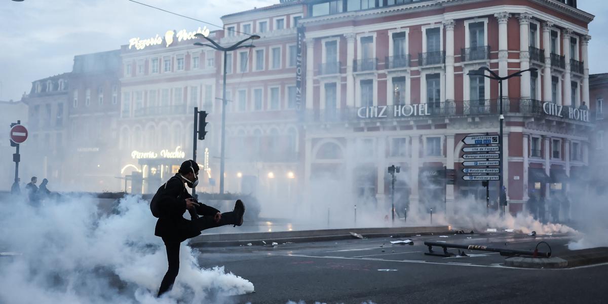 Könnygázgránátot rúg vissza a rendőrség felé egy francia tüntető egy héttel a nyugdíjreform szavazás nélküli elfogadtatása után.