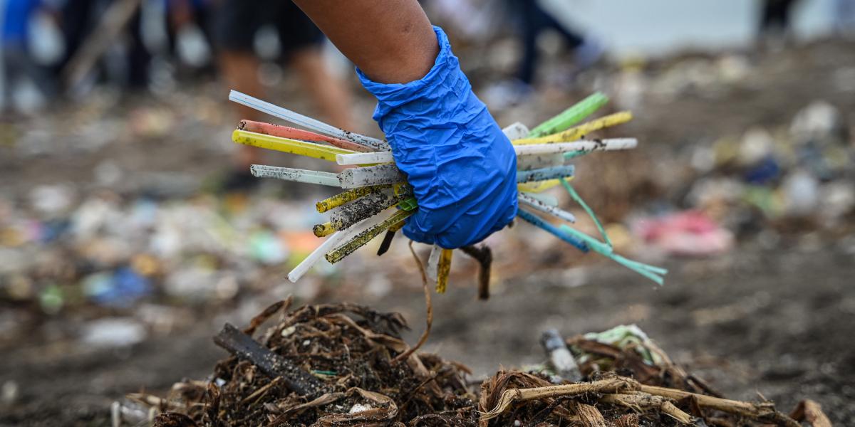 Egy önkéntes eldobott műanyaghulladékot, köztük szívószálakat gyűjt a Fülöp-szigeteki Manilában található Baseco Beachen 2024. szeptember 21-én.