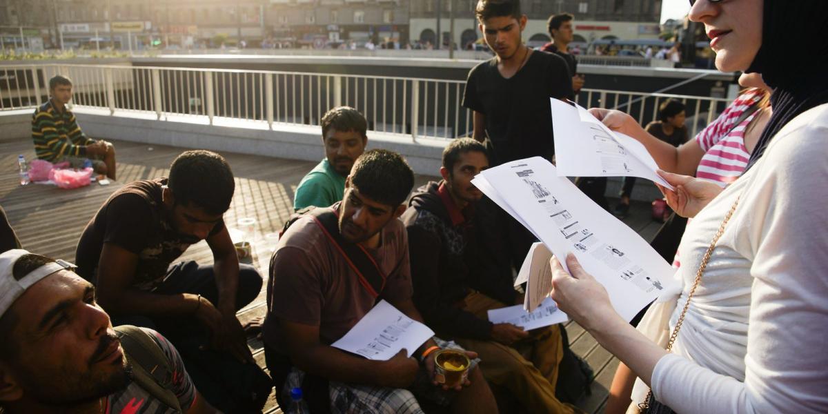  A Facebookon szerveződött civil csoport egyik tagja információkat ad migránsoknak a budapesti Keleti pályaudvar előtt 2015. júl