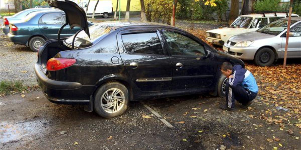 A helyi Lavriscseva utcai többszintes lakóépület előtti parkolóban felrobbantott gyalogsági gránát szilánkjainak nyomait nézi au