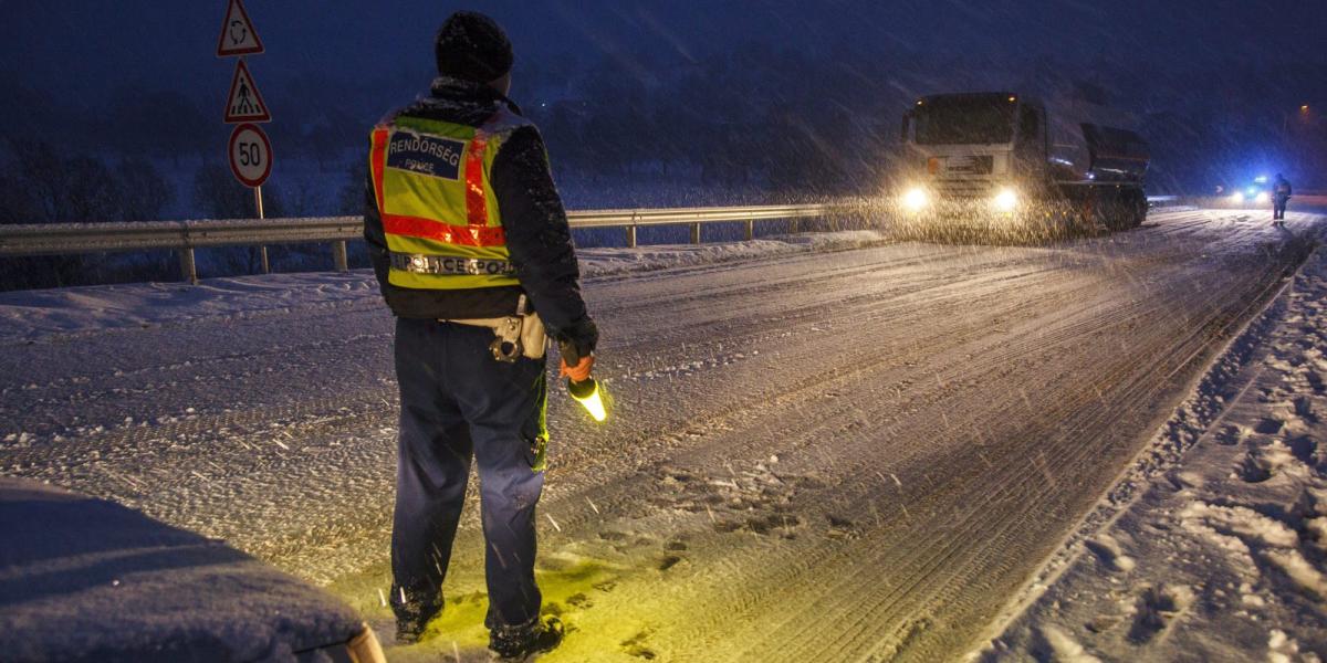 Rendőrök irányítják a forgalmat egy hóban elakadt kamion mellett Nagykanizsán. MTI Fotó: Varga György