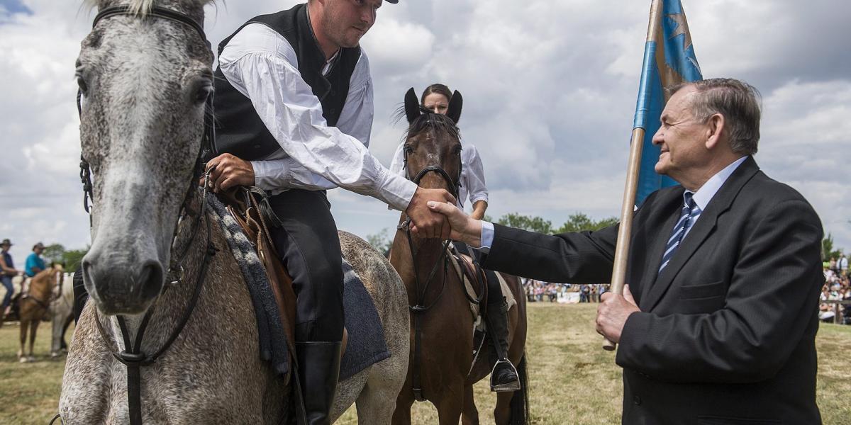 Lezsák Sándor, az Országgyűlés alelnöke (j) átveszi a székely zászlót Abos Zsolttól, a Csíksomlyóról érkezett lovas küldöttség v