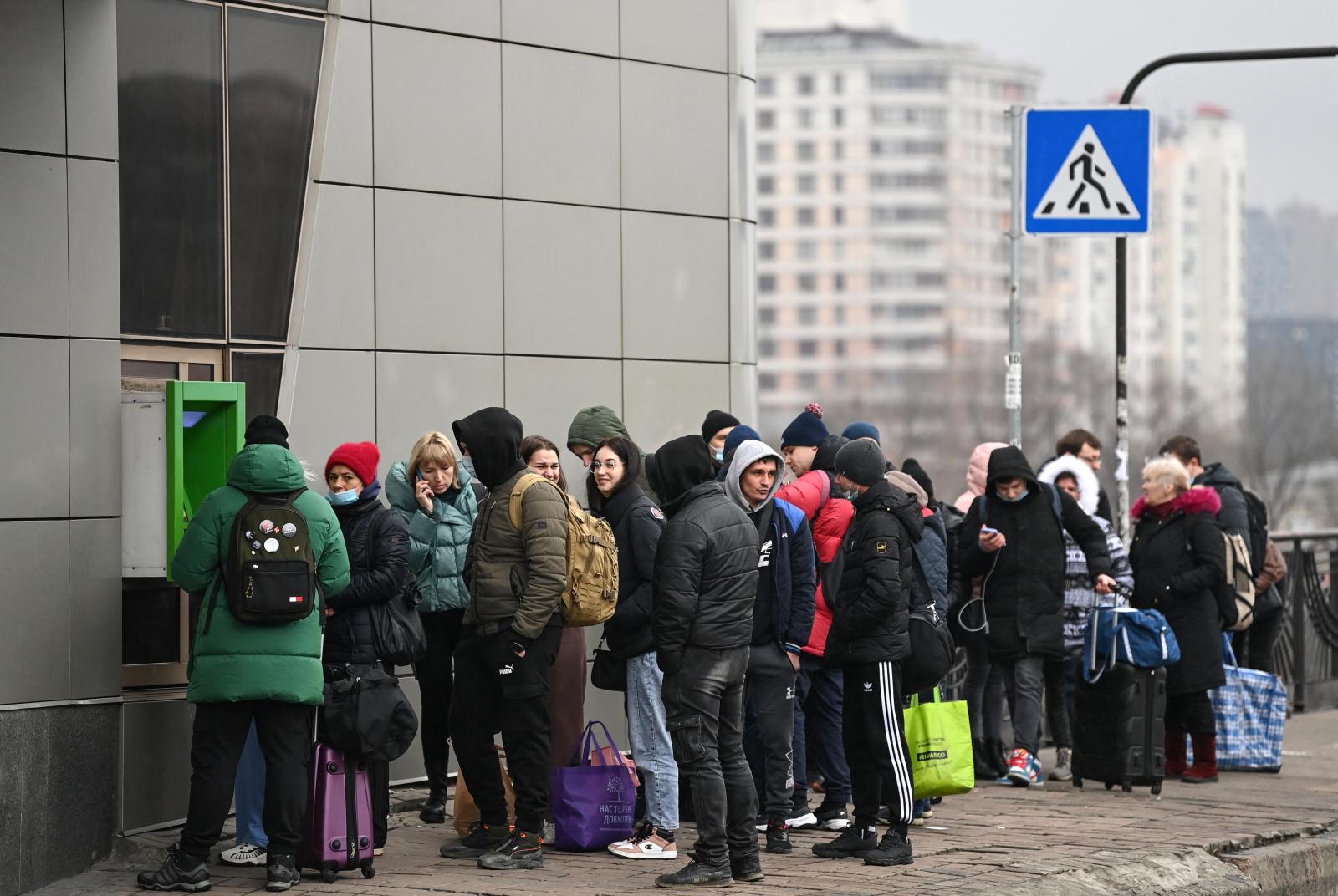 Az emberek sorban állnak, hogy pénzt vegyenek ki egy pénzautomatánál Kijevben