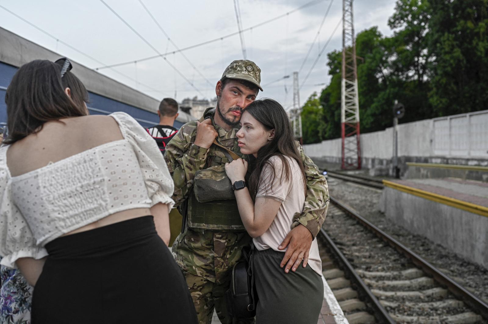 Egy férfi ül és nézi az ukrán katonák képeit ábrázoló emlékfalat, akiket azóta öltek meg, hogy Oroszország februárban megszállta Ukrajnát, Kijev központjában 2022. július 26-án.