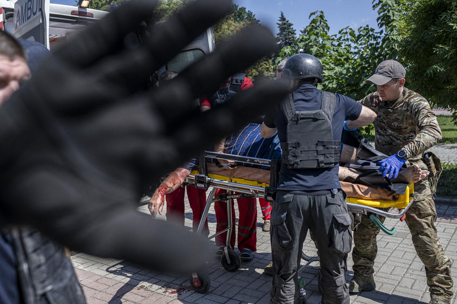 Egy férfi ül és nézi az ukrán katonák képeit ábrázoló emlékfalat, akiket azóta öltek meg, hogy Oroszország februárban megszállta Ukrajnát, Kijev központjában 2022. július 26-án.