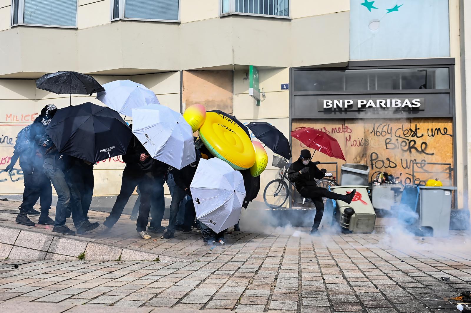 Könnygázgránátot rúg vissza a rendőrség felé egy francia tüntető egy héttel a nyugdíjreform szavazás nélküli elfogadtatása után.