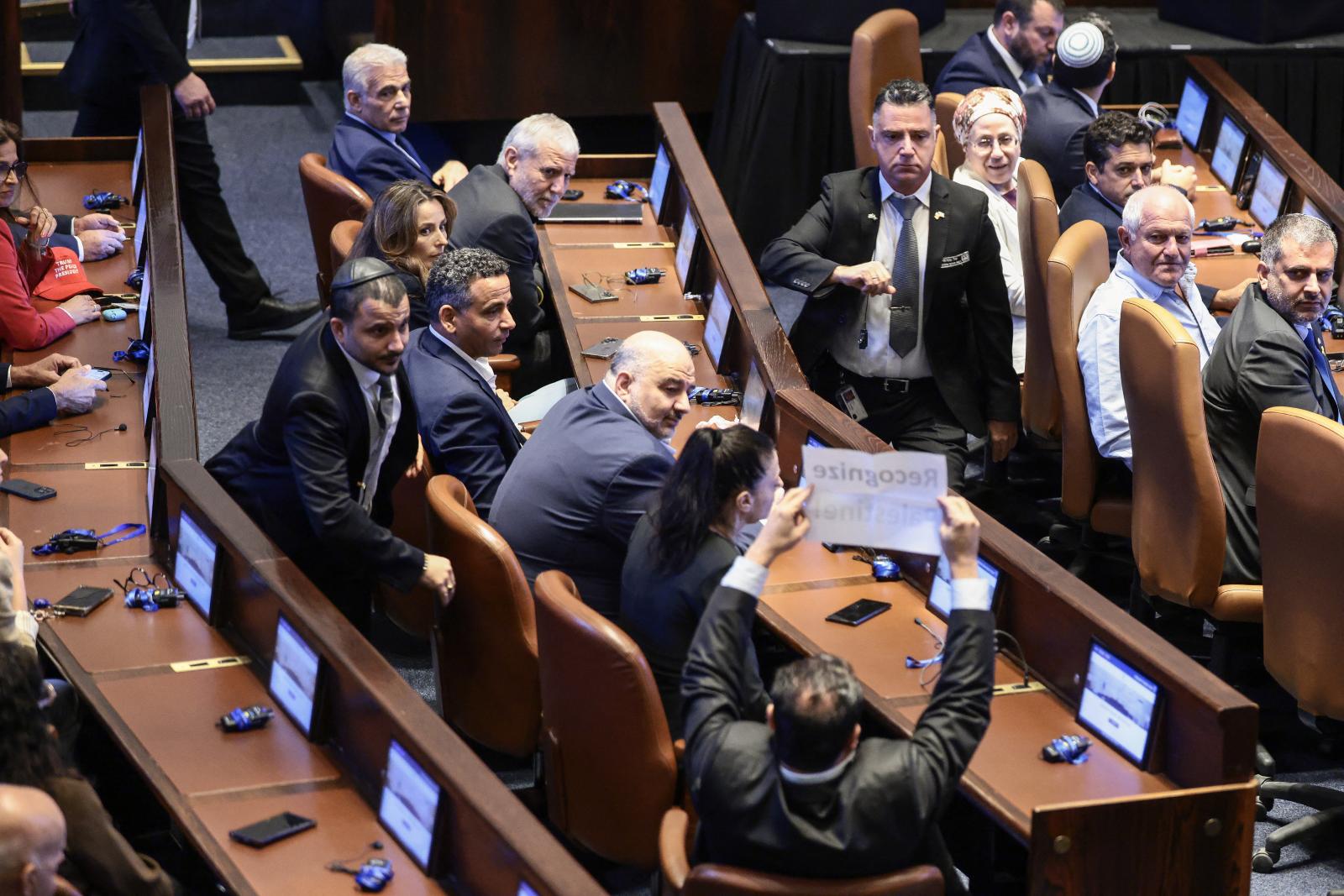 Ayman Odeh "Ismerjük el Palesztinát” feliratú transzparenst tart fel Donald Trump beszéde közben a Kneszetben október 13-án