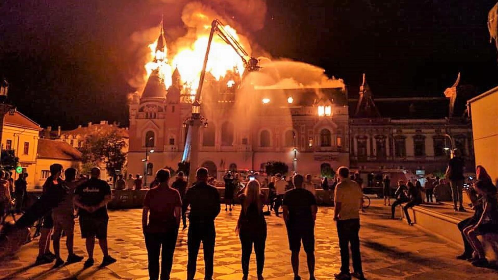 Járókelők nézik, fotózzák a lángoló püspöki palotát