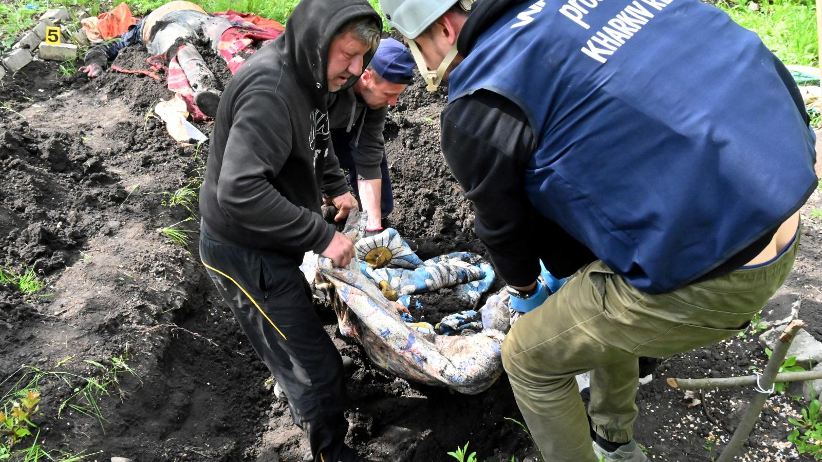 Helyi lakosok segítenek holttesteket exhumálni egy sírból a Harkivhoz közeli Stepanky faluban.