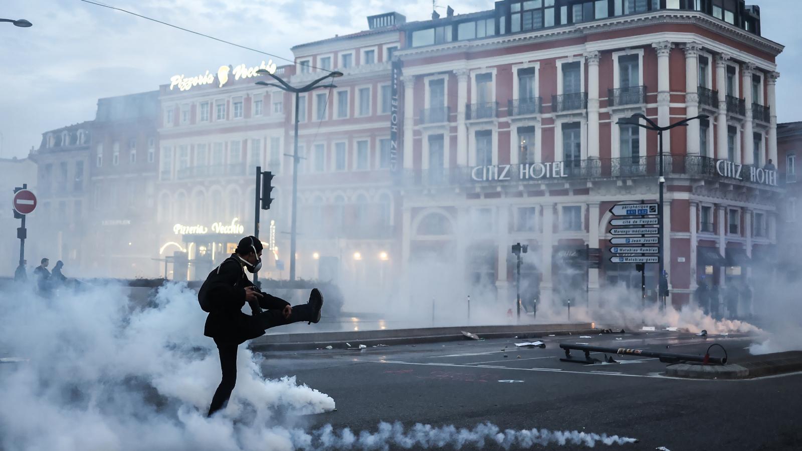 Könnygázgránátot rúg vissza a rendőrség felé egy francia tüntető egy héttel a nyugdíjreform szavazás nélküli elfogadtatása után.