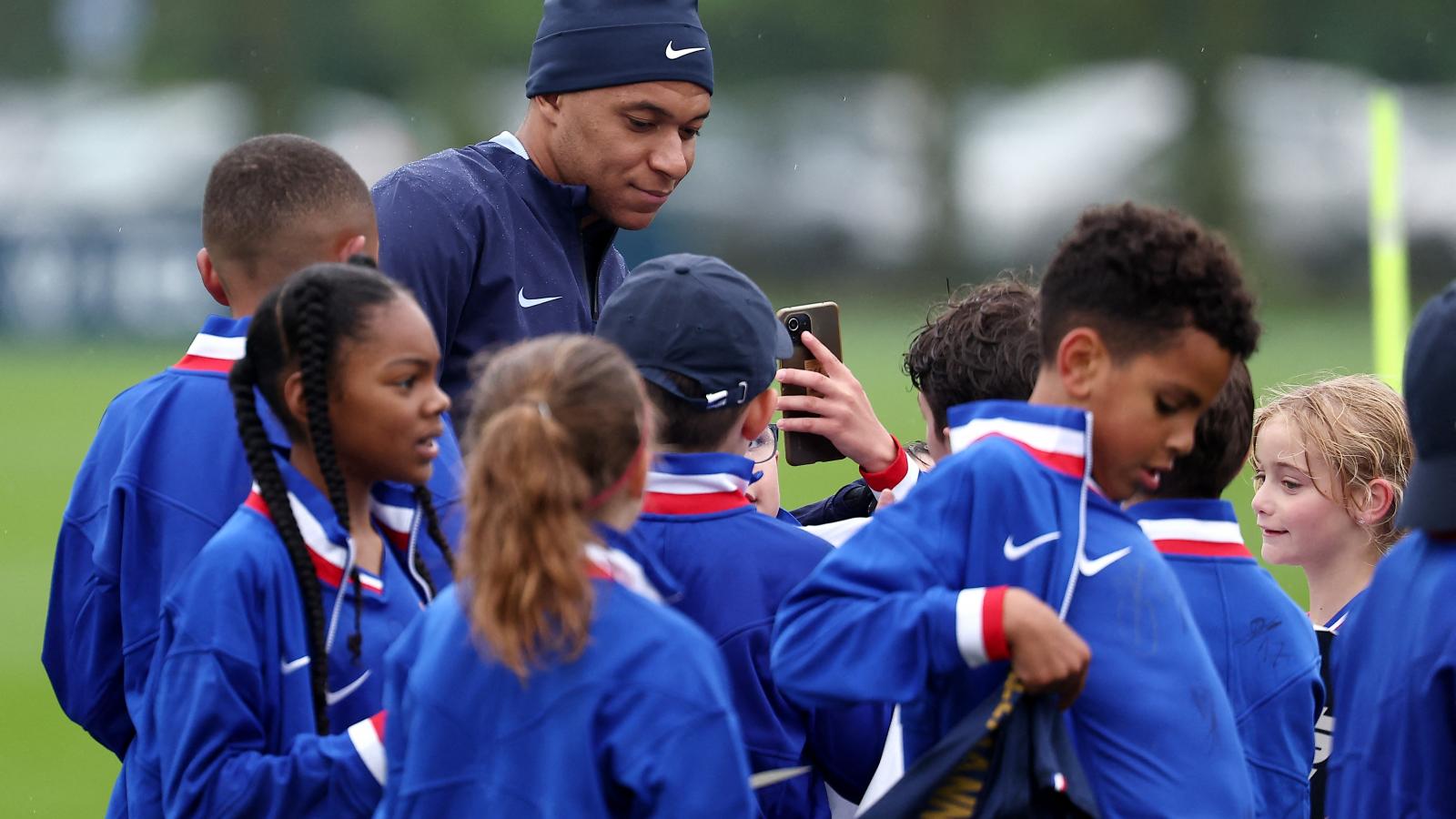 Kylian Mbappé rajongó gyermekek gyűrűjében a francia válogatott edzése előtt