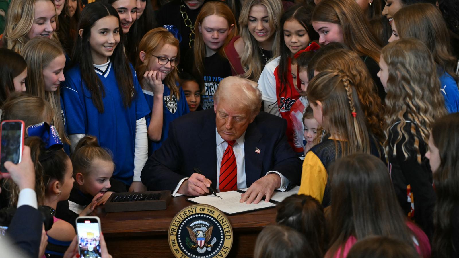 Trump elnök női sportolók, köztük kislányok gyűrűjében írta alá a rendeletet a Fehér Házban megrendezett nyilvános eseményen 