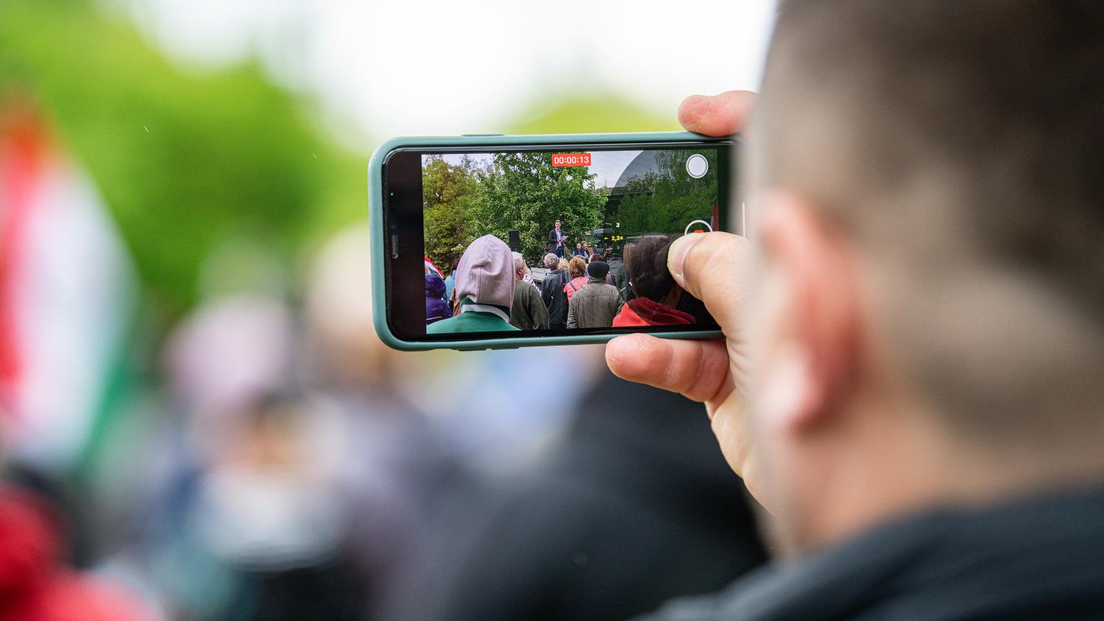 Illusztráció: Magyar Péter beszédét videózó férfi Szarvason 2024. április 18-án 
