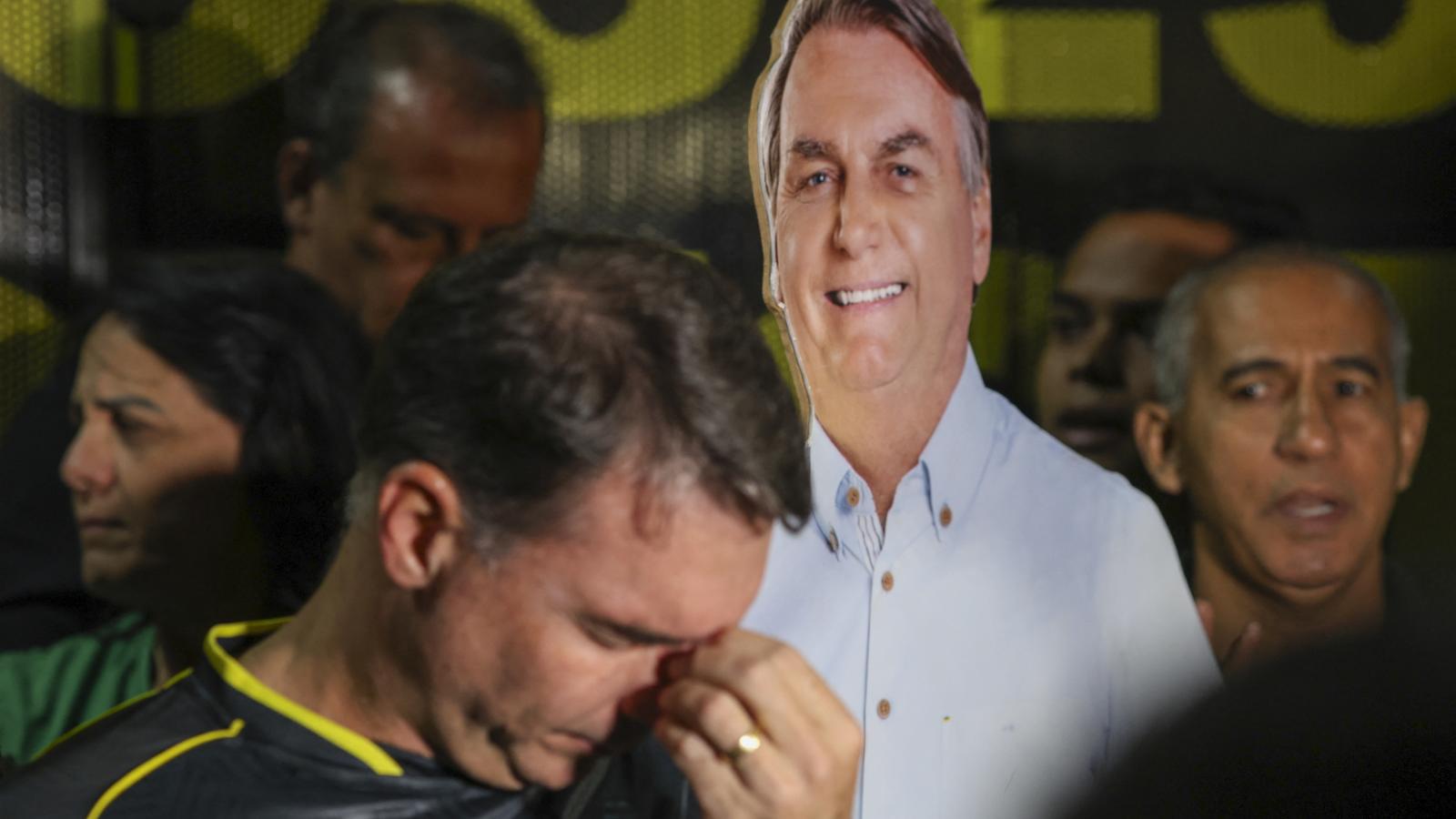 Flávio Bolsonaro szenátor szomorkodik apja karton arcmása előtt egy szombati megmozduláson