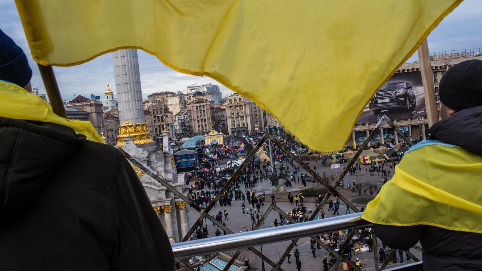 Ukrán zászlóba "öltözött" kormányellenes tüntetők figyelik demonstráló társaikat a Függetlenség terén. Fotó: Brendan Hoffman/ Ge