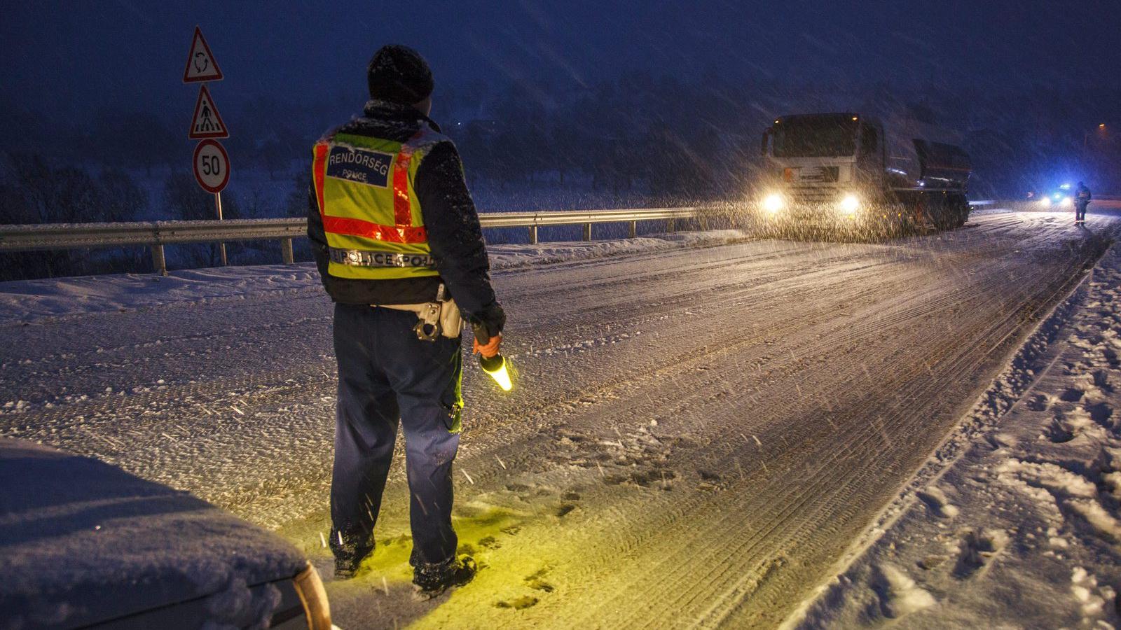 Rendőrök irányítják a forgalmat egy hóban elakadt kamion mellett Nagykanizsán. MTI Fotó: Varga György