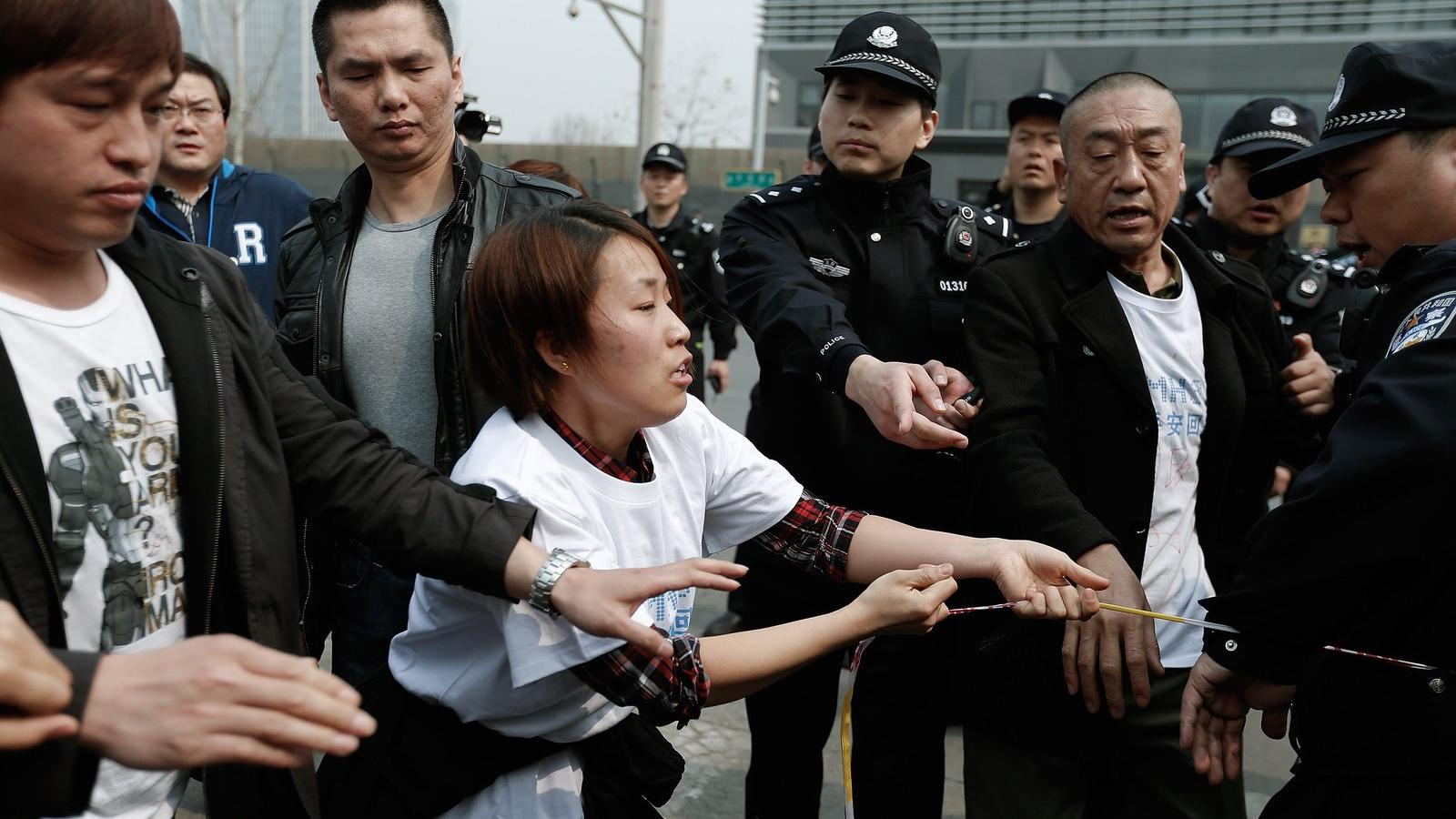 Dühös hozzátartozók mennek neki a rendőröknek a pekingi maláj nagykövetség épülete előtt. Fotó: Lintao Zhang/Getty Images