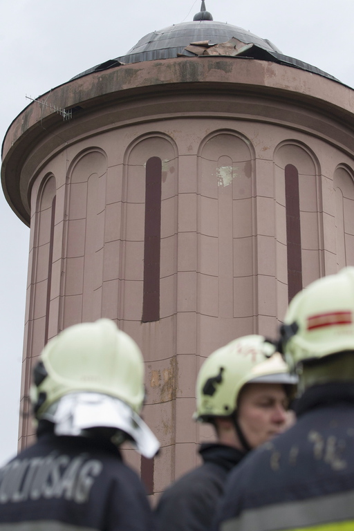 Az erős szél miatt a tűzoltók nem tudnak beavatkozni a magasból mentő eszközeikkel, a víztorony épületéből pedig nem lehet feljutni a tetőre. Fotó: Varga György/MTI