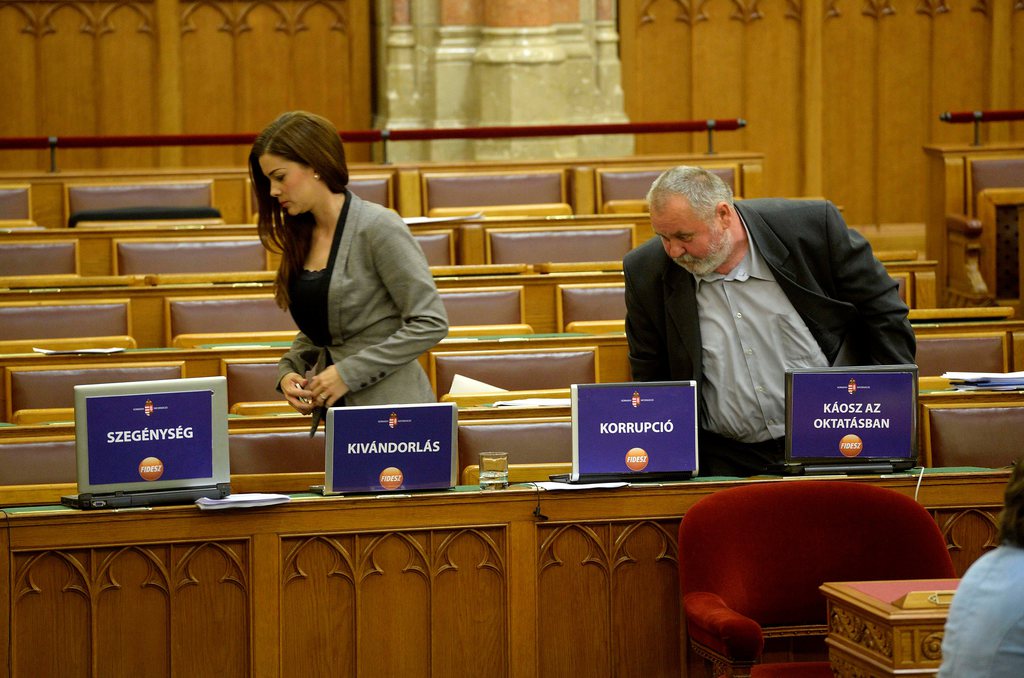 Demeter Márta és Gőgös Zoltán szocialista képviselők távoznak az MSZP-frakció tagjainak "Szegénység", "Kivándorlás", "Korrupció" és "Káosz az oktatásban" feliratokkal felmatricázott laptopjai mellett a menedékjogról szóló törvénymódosítás általános vitájáról. MTI Fotó: Bruzák Noémi